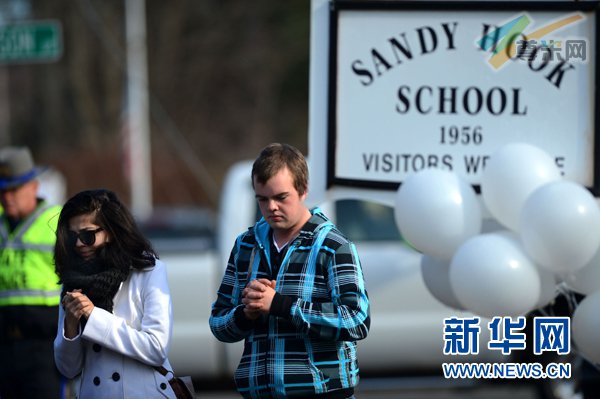 12月15日，两名居民在发生枪击事件的桑迪胡克小学附近街区进行悼念。新华社记者王雷摄